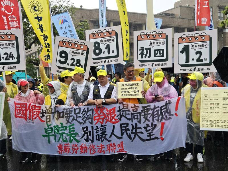 尊嚴勞動修法聯盟13日在大雨下,在行政院門口呼籲內閣儘速修法增加國定假日天數與提高雇主勞退提撥。(Photo by 呂翔禾/台灣醒報)